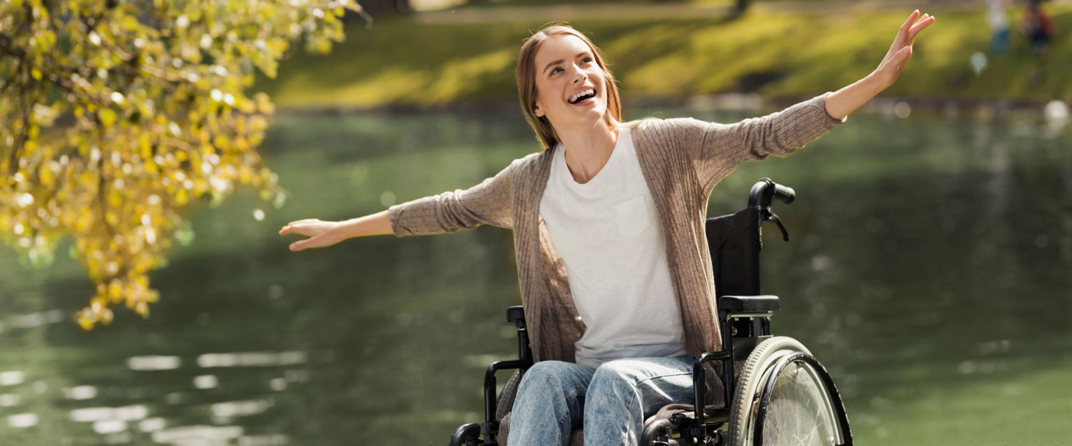 Frau sitzt lächelnd im Rollstuhl