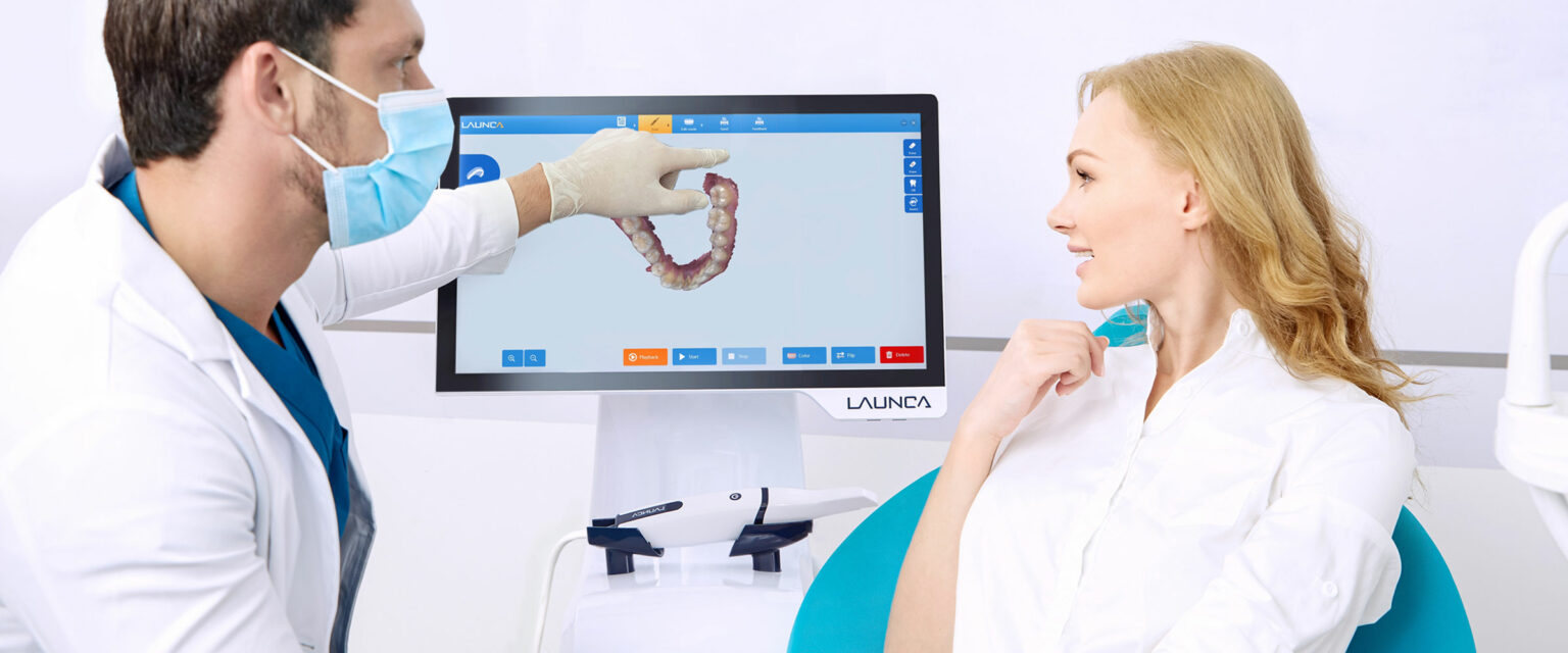 Zahnarzt zeigt Patientin 3D-Scanaufnahme über Bildschirm.