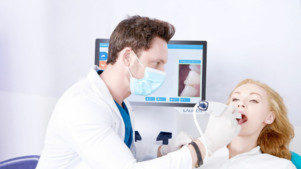 Zahnarzt scannt mit Intraoralscanner Zähne von Patientin.