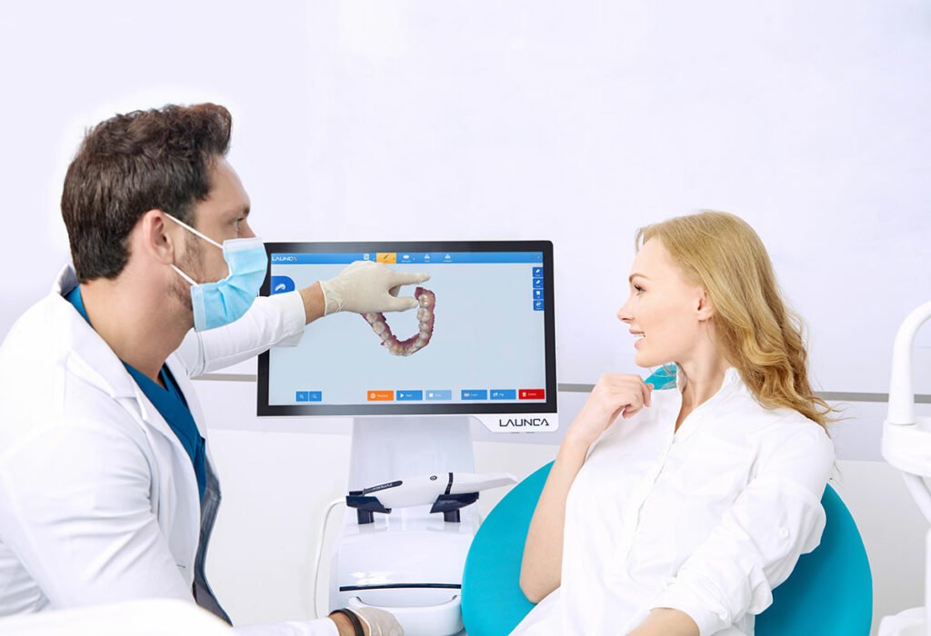 Zahnarzt zeigt Patientin 3D-Scanaufnahme über Bildschirm.