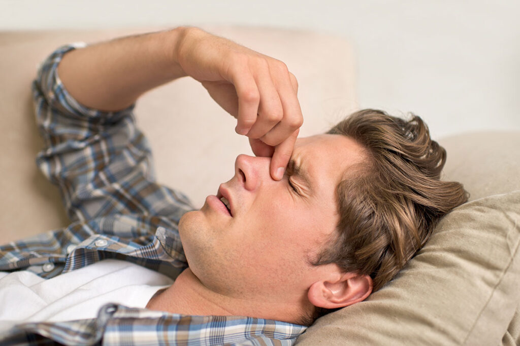 Mann liegt erschöpft auf der Couch
