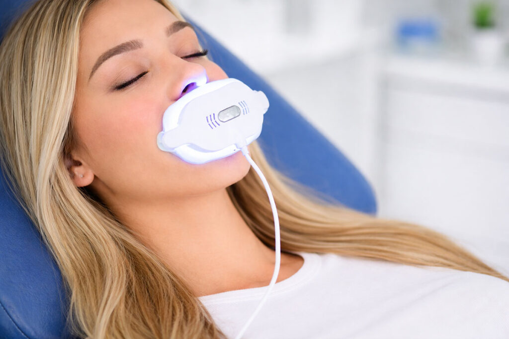 Frau bei Zahnbleaching-Behandlung mit neuem Bleaching-Gerät Beyond II Ultra